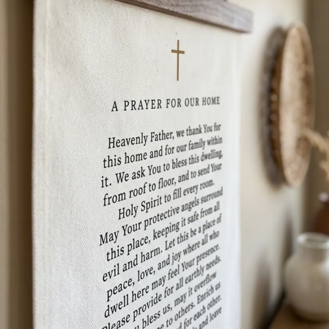 A prayer for our home hanging on a wall, with a wooden frame and a cross symbol.