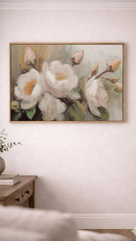 a large painting of white flowers hanging on a wall above a wooden table.